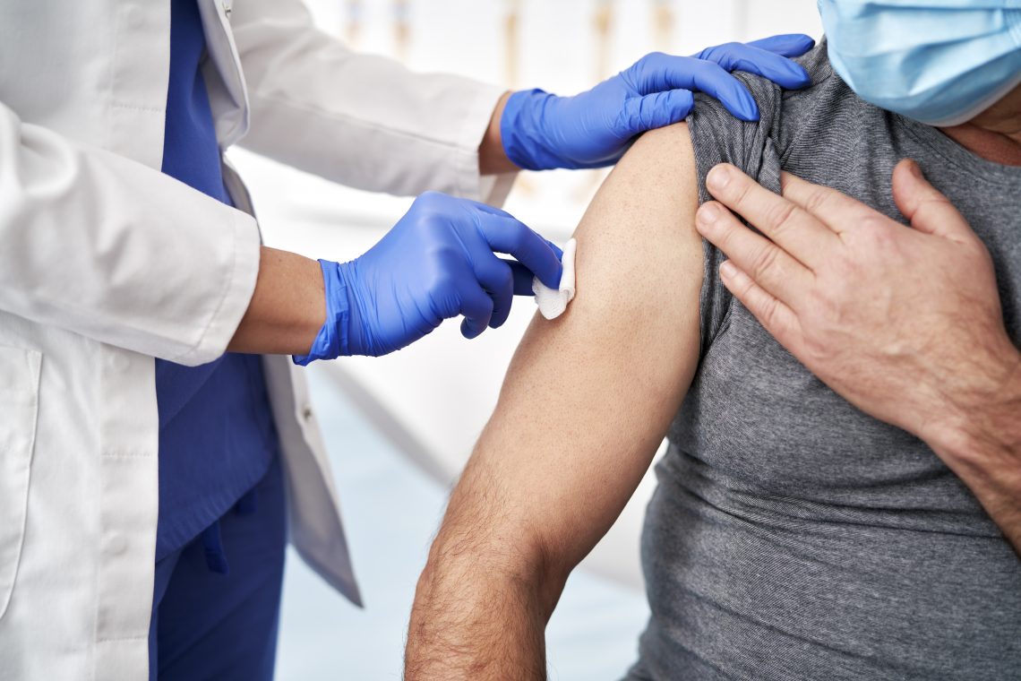Médico limpia con algodón el brazo a un paciente antes de vacunarse contra el COVID